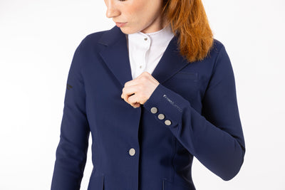 Close up of neptune blue Freejump Women's Show coat to show "freejump" on left sleeve and Laser-cut perforated bands on the bottom of the pockets and on the collar