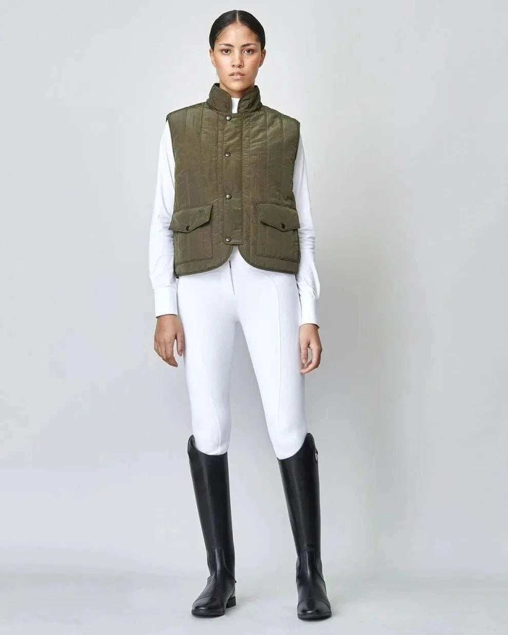 The Green Quilted Riding Vest offers a boxy silhouette with a stand-up collar, front zipper, and placket with easy press studs. The exterior is both wind-proof and water-repellent while Primaloft Padding insulates to provide optimal warmth throughout your ride. Feature two front pockets, two invisible side seam pockets, and an inner pocket. Cut from an Italian fabric, and sewn in Europe.